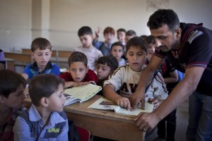 Un insegnante con gli alunni in una scuola di Aleppo (Ansa)